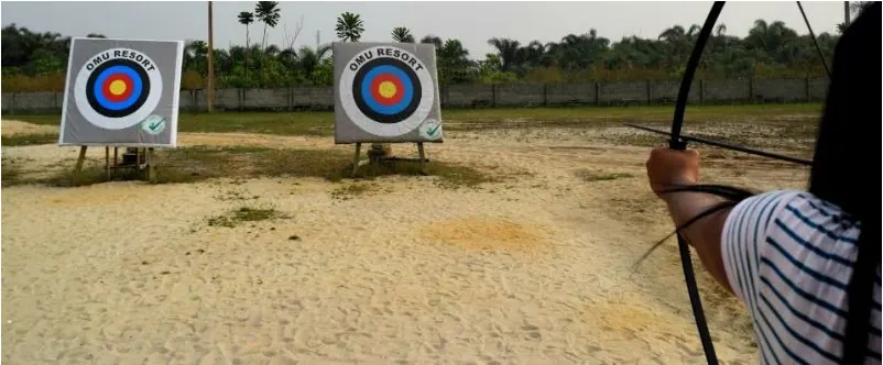 An archer drawing a bow at an outdoor range in Nigeria