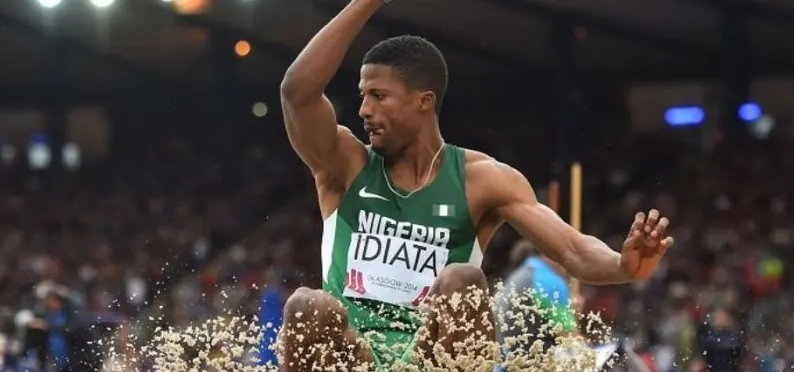 Nigerian athlete in green celebrating with the national flag