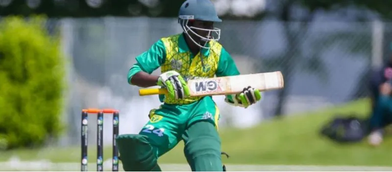 A Nigerian batter in green and yellow plays a shot in front of the stumps