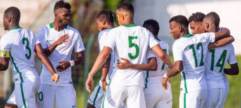 Nigeria players in white celebrating a goal together