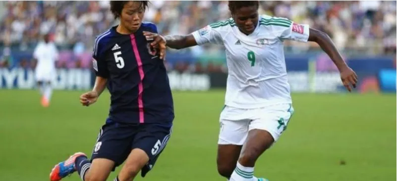 A Nigerian player in white challenging a Japan player