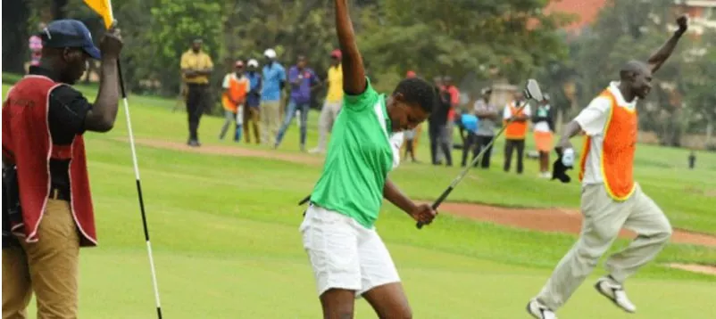 A golfer celebrating a putt as caddies look on