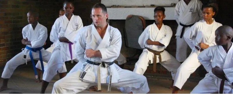A karate instructor leading Nigerian students through a stance