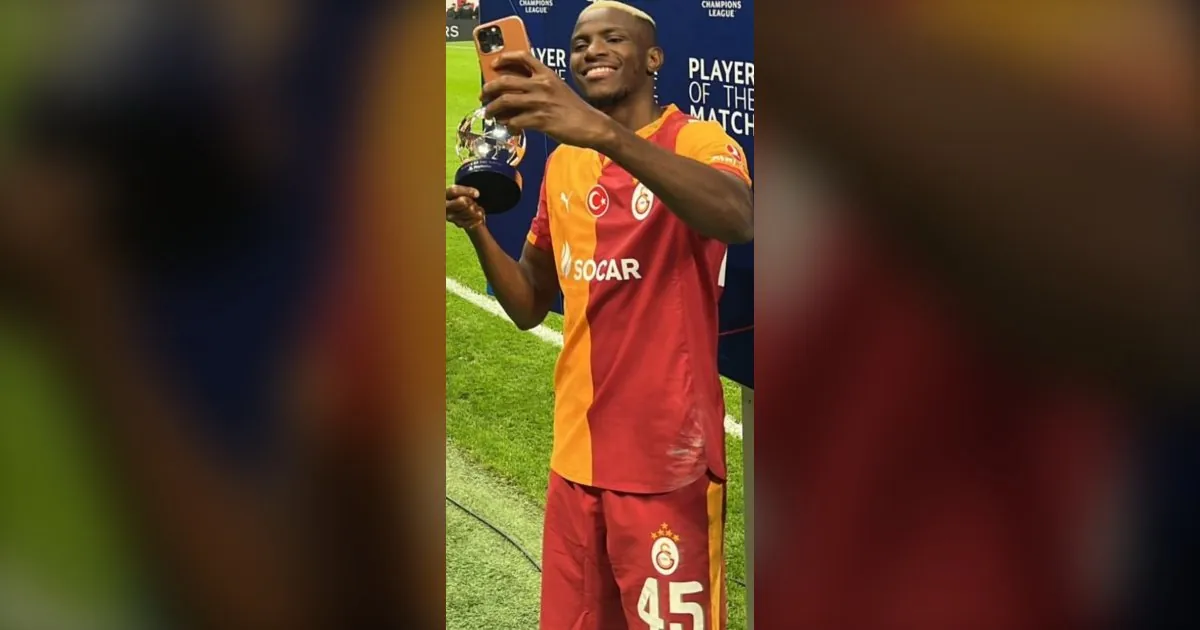Victor Osimhen in a Galatasaray shirt holding a phone on the pitch