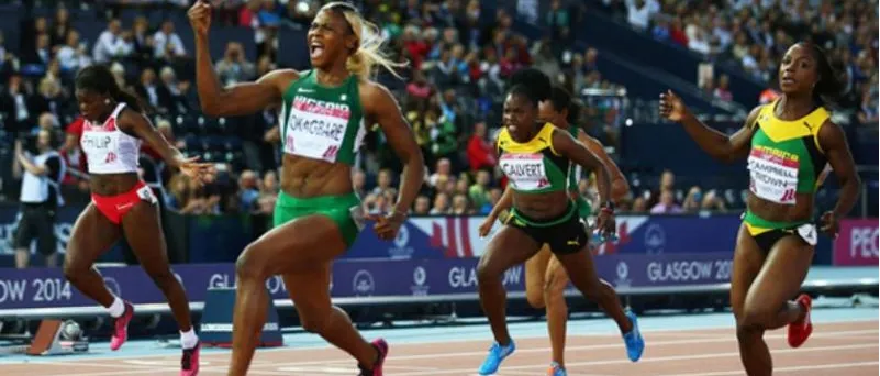 A Nigerian sprinter in green and white wins her race ahead of her rivals