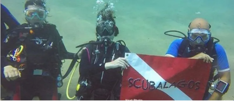 Divers holding a ScubaLagos dive flag underwater