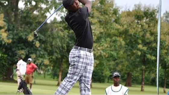 Nigerian golfer finishing a swing on a tree-lined course