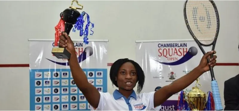 A Nigerian champion lifts the trophy at the Chamberlain Squash Open